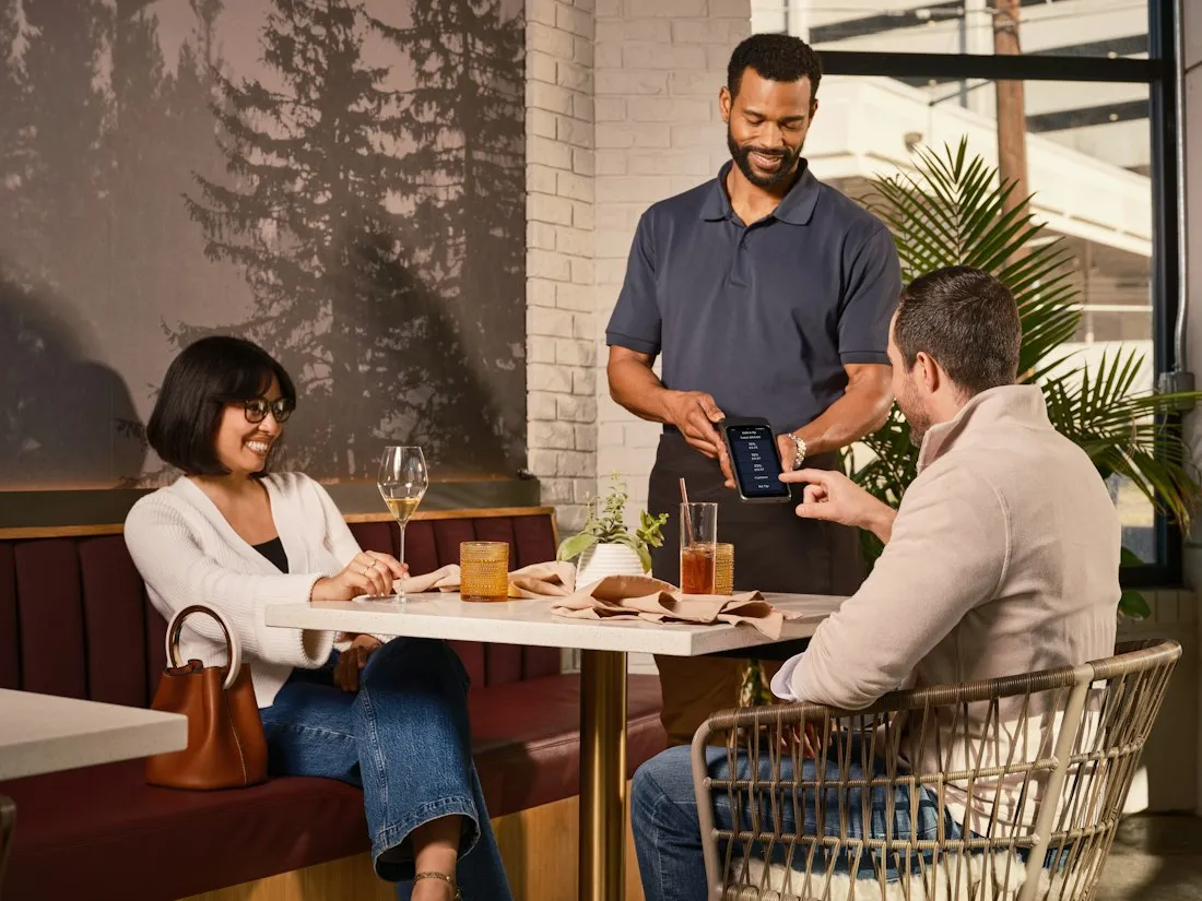 A waiter with a tablet at a restaurant table