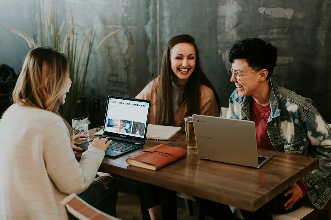 A small team laughing together around laptops